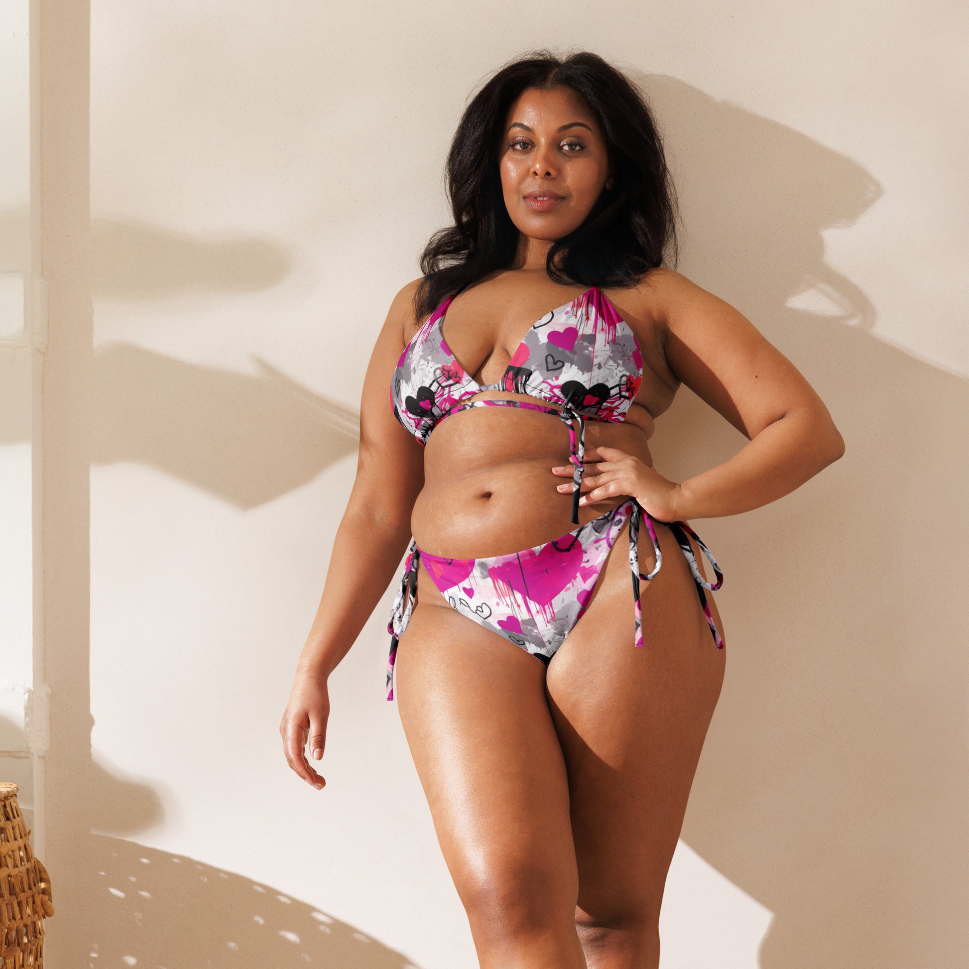 Celebrate confidence and radiant style as a beautiful woman leans against a wall, donning the "Pink Love" Bikini by MeaKulpa. The allure of this vibrant swimwear shines through, proving that glamour knows no size. Our alternate text captures the essence of self-assured elegance, inviting everyone to embrace the empowering spirit of MeaKulpa's swimwear collection. Elevate your poolside presence with a touch of boldness and a dash of glamour that's inclusive and utterly fabulous.