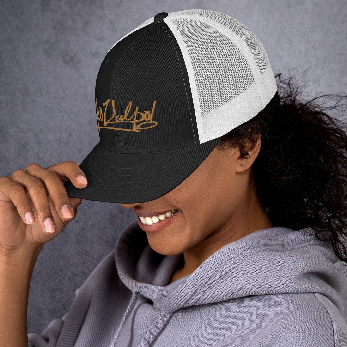 Side Angle of the MeaKulpa Trucker Cap in Black and White - Explore the sleek profile of the MeaKulpa Trucker Cap. The gold emblem glistens against the black front, while the white mesh back adds a touch of contrast. It's the perfect blend of modern sophistication and vintage charm.