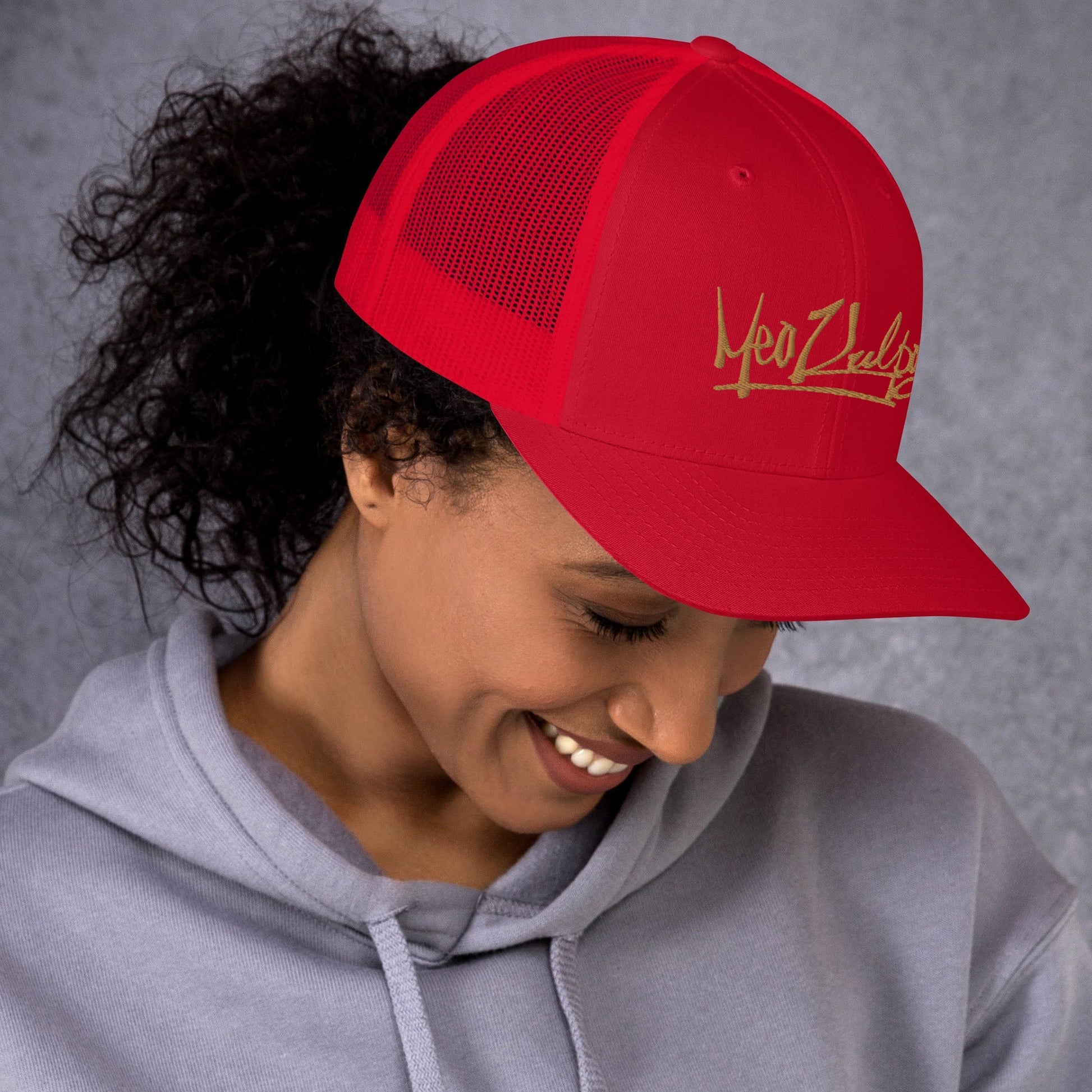 MeaKulpa Red Trucker Cap can be worn by both men and women -  Experience the MeaKulpa lifestyle in the great outdoors. This lifestyle shot captures the Red Trucker Cap in action, blending seamlessly with nature. The gold logo adds a touch of opulence to your everyday adventures.