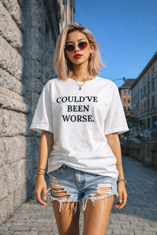 Gen Z girl wearing a white t-shirt with text  Could've been worse and denim shorts in an urban setting