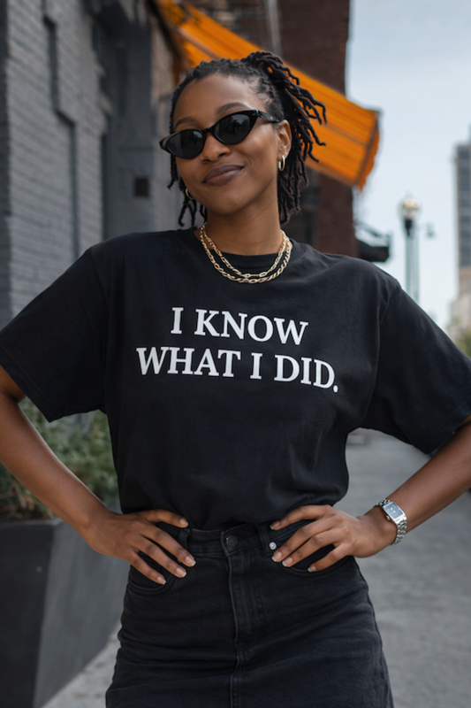 Person wearing a black t-shirt with 'I KNOW WHAT I DID' text, standing outdoors.